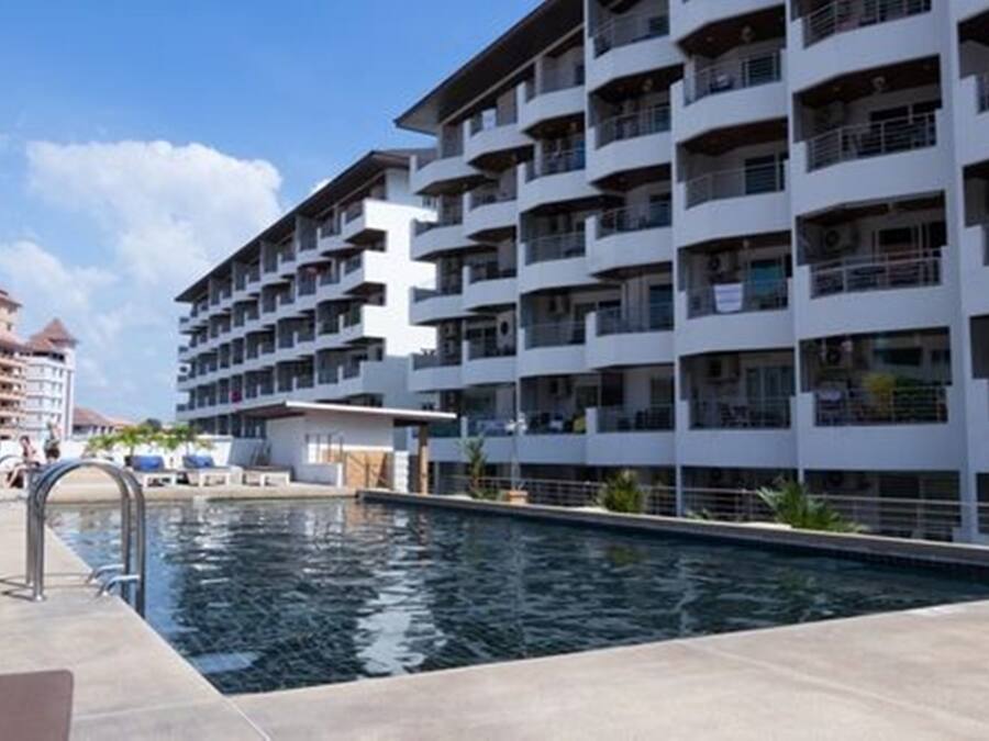 Un hotel moderno con piscina, varios balcones y vistas a otros edificios.