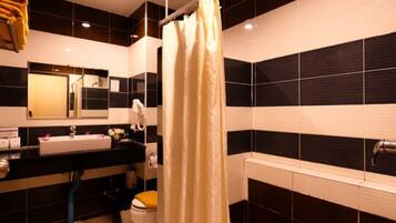 A bathroom with a black and white tiled wall, a white sink, a mirror, and a shower curtain.