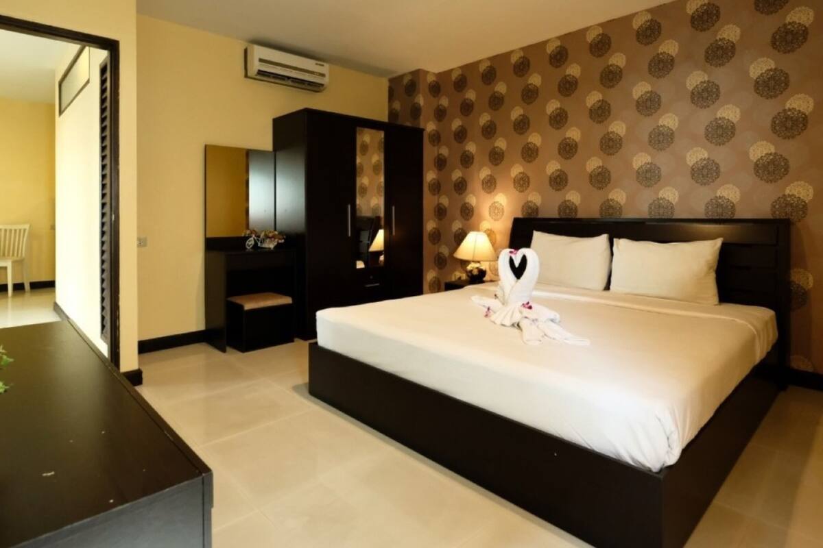 Ein Hotelzimmer mit einem großen Bett, einem Kleiderschrank, einem Schreibtisch und einem Spiegel.