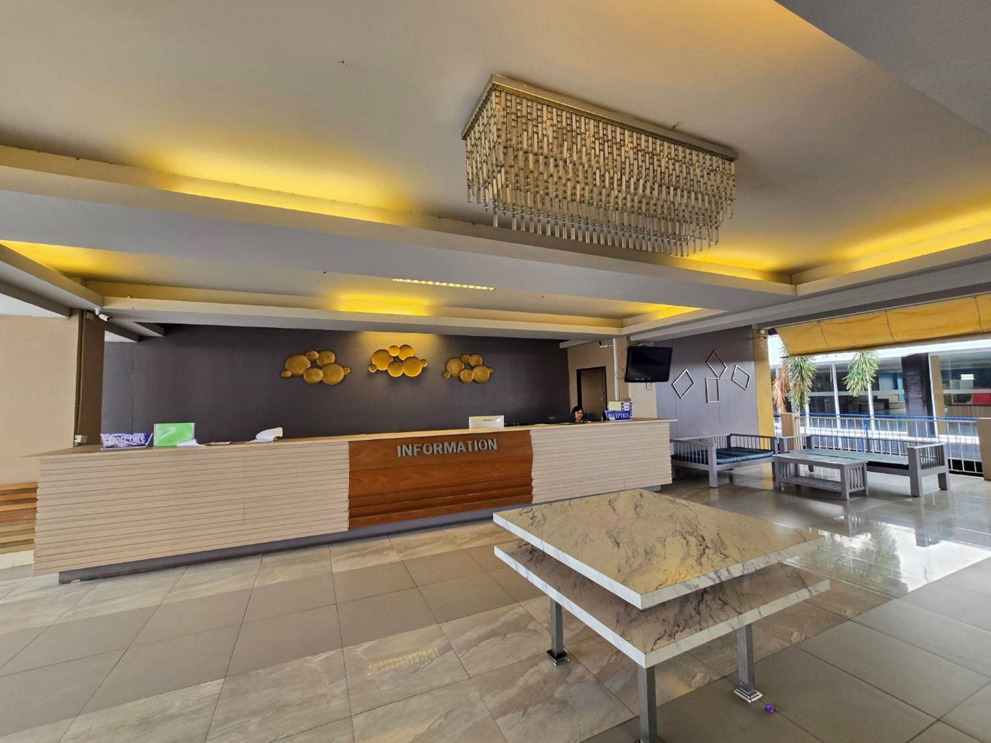 A reception area with a marble table, a reception desk, and a wall-mounted chandelier.