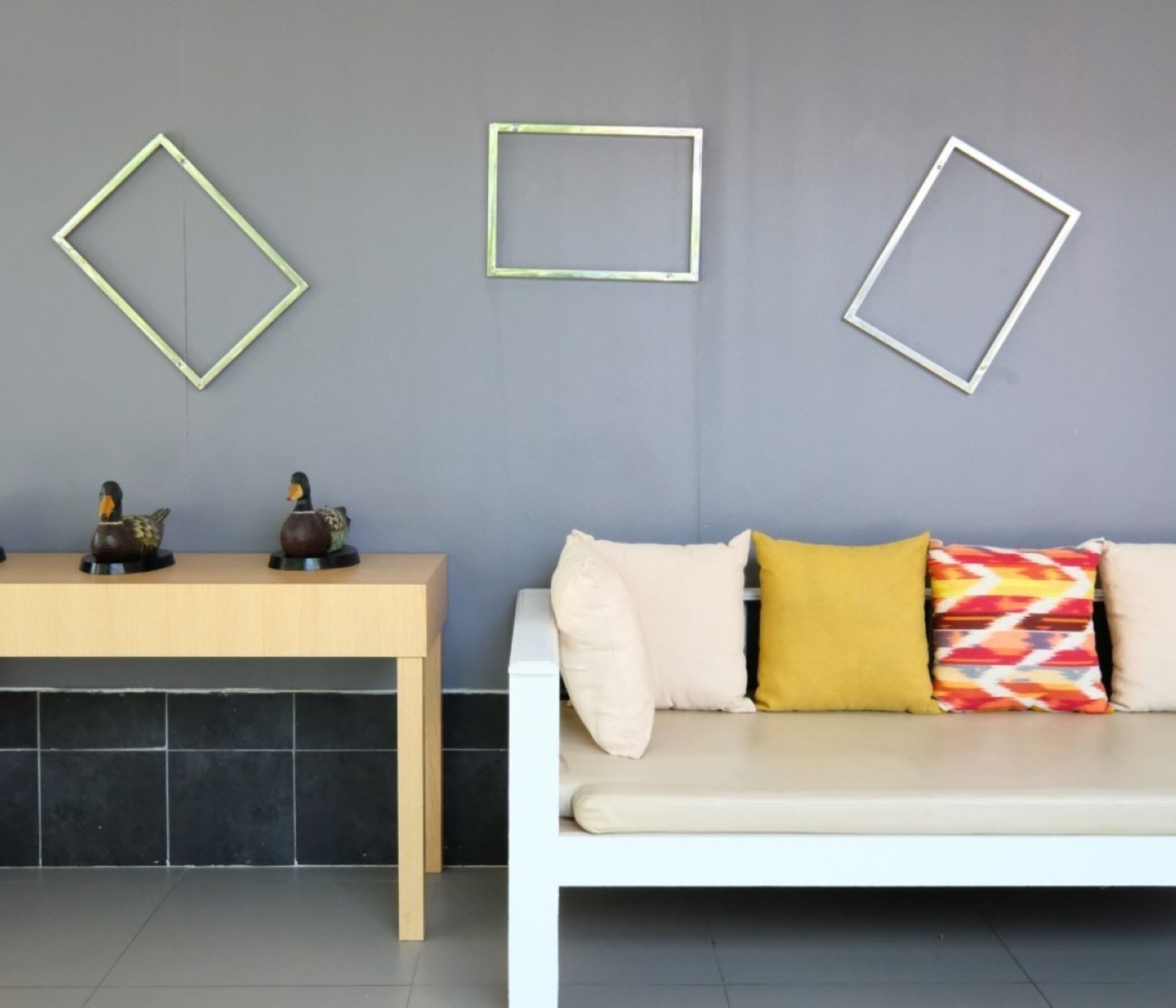 Un salón moderno con un sofá blanco, una mesa de centro de madera y figuritas decorativas de patos.