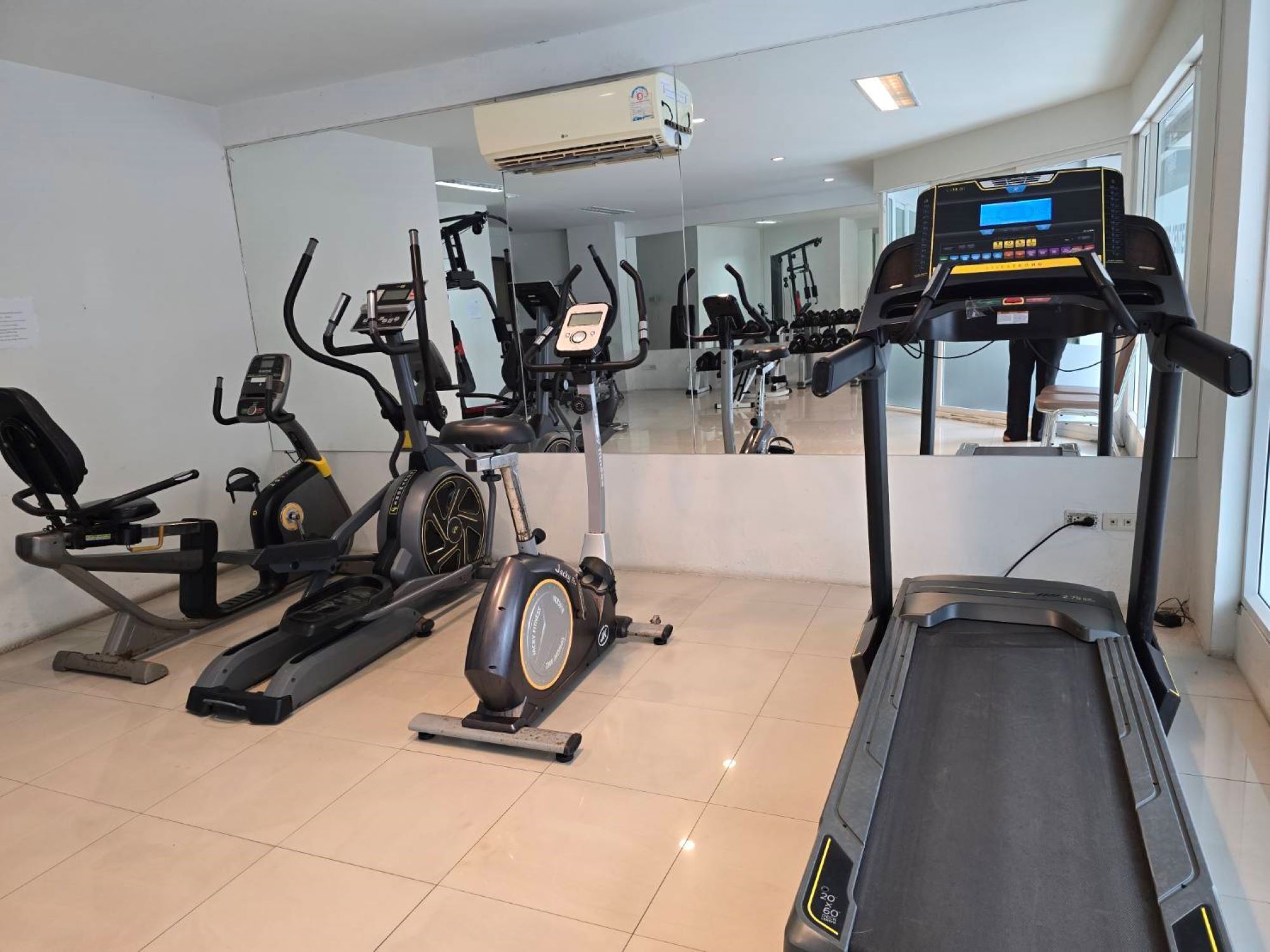 A gym with various exercise equipment, including treadmills, stationary bikes, and elliptical machines.