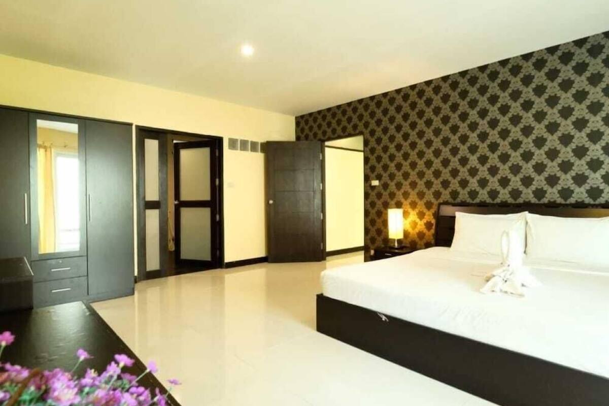 Ein Hotelzimmer mit einem großen Bett, einem Kleiderschrank, einem Spiegel und einer Wand mit Muster.