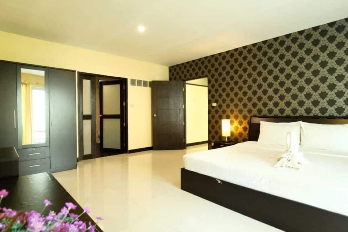 A hotel room with a large bed, a wardrobe, a door, and a patterned wall.