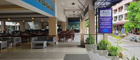 Tilava hotellin aula, jossa on sininen kyltti, jossa lukee ”JOMTIEN PLAZA RESIDENCE”, sekä kyltti, joka osoittaa ravintola- ja huonealueelle.