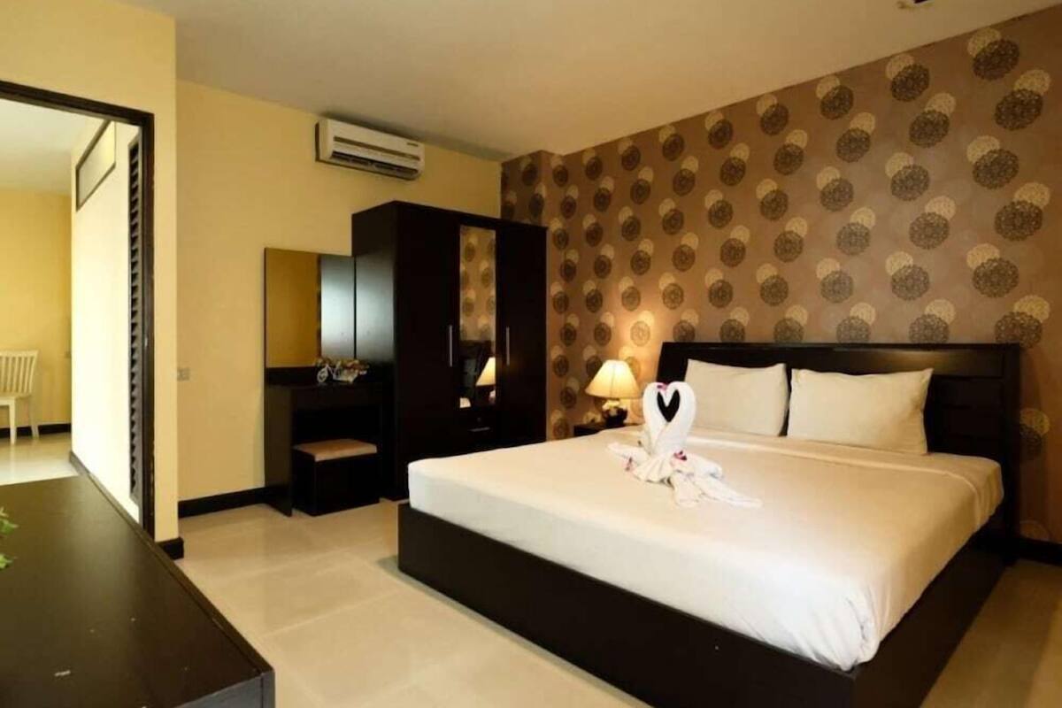 Ein Hotelzimmer mit einem großen Bett, einem Schreibtisch, einem Kleiderschrank und einer Klimaanlage.