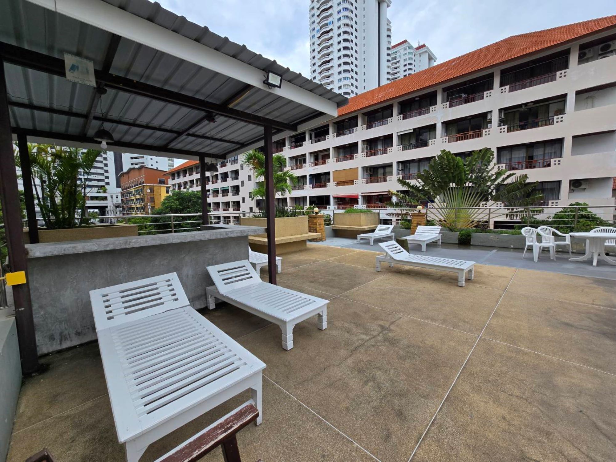 A rooftop patio with white lounge chairs and a covered seating area.