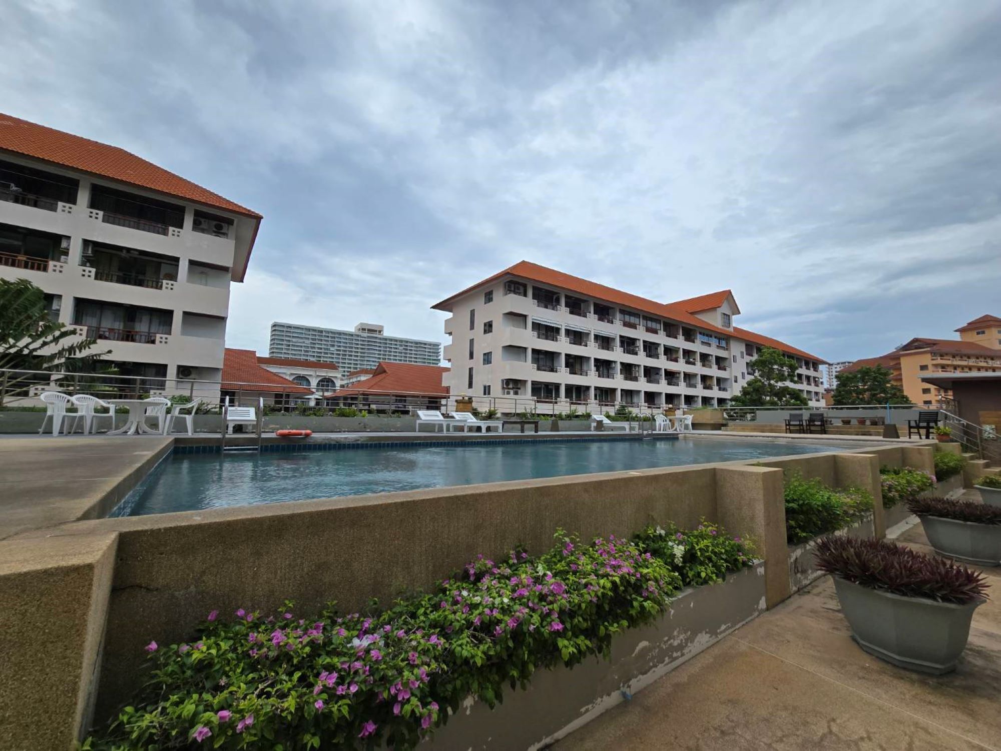 A hotel with a swimming pool, outdoor seating, and a garden area.