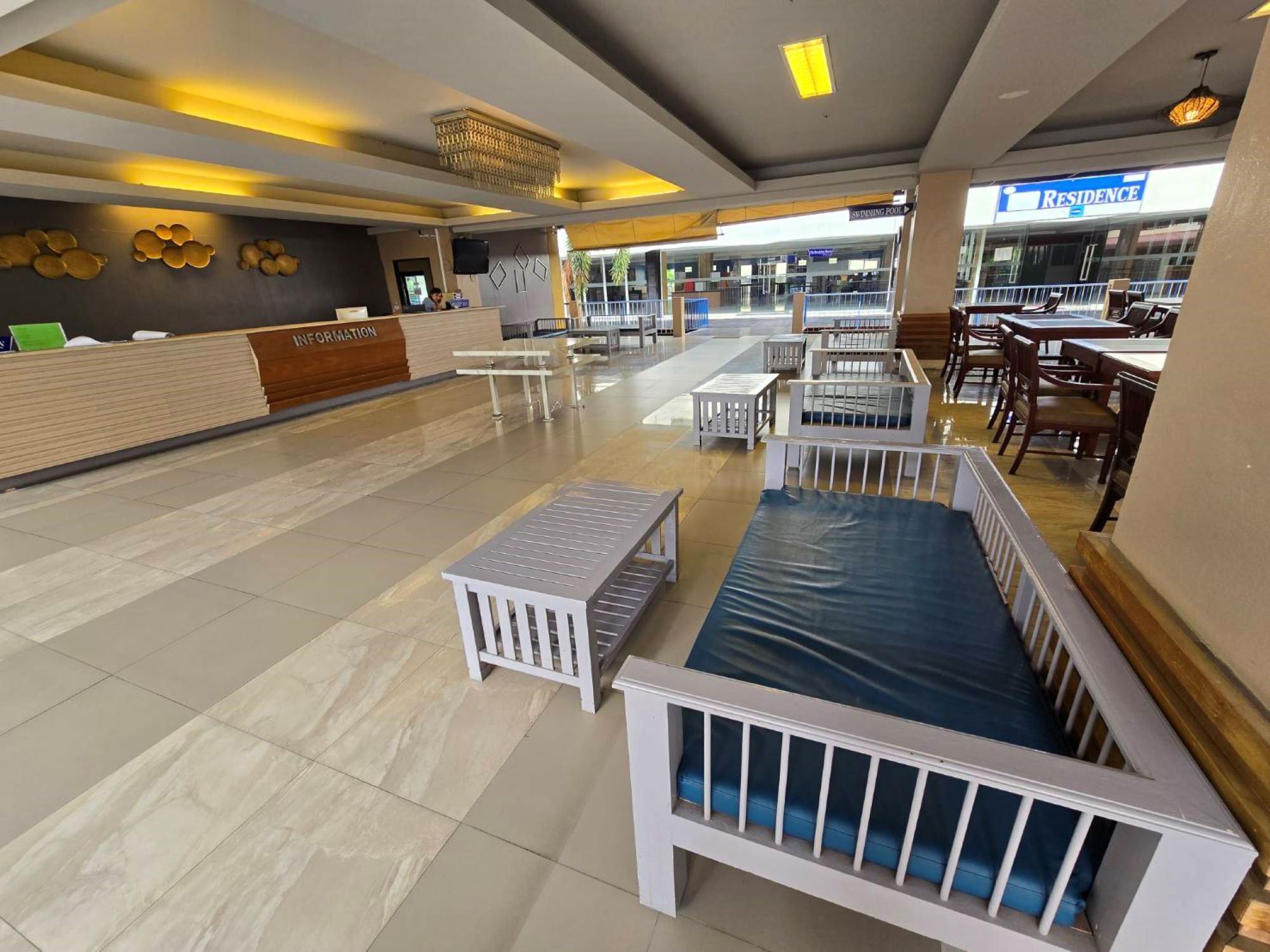 A spacious lobby with a reception desk, seating areas, and a 'Residence' sign in the background.