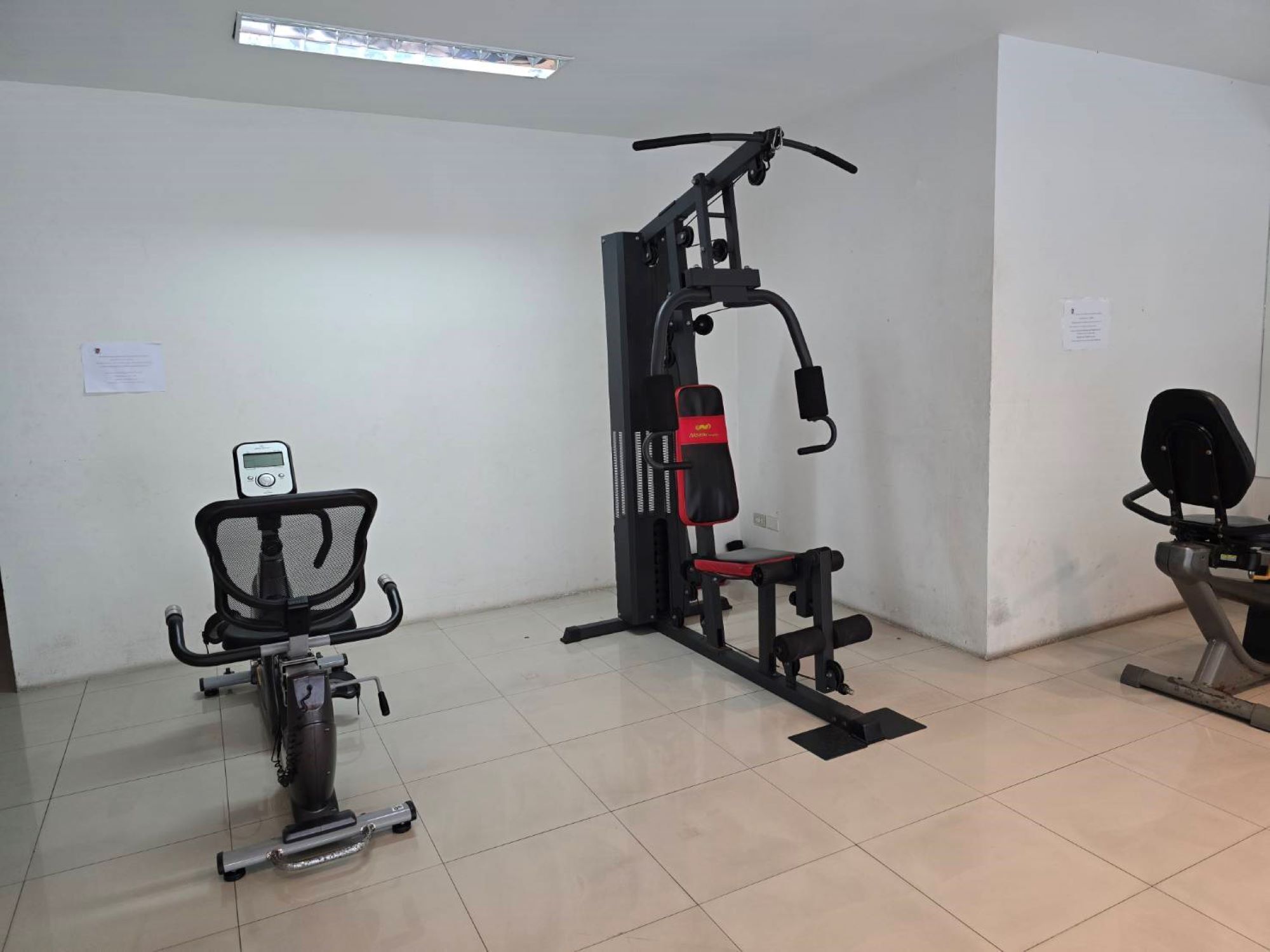 Un gimnasio con equipo de ejercicio, una bicicleta estática y un banco para pesas.