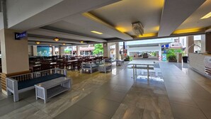 Un vaste espace intérieur aménagé avec différents coins salon, un comptoir d’accueil et une vue sur l’extérieur.