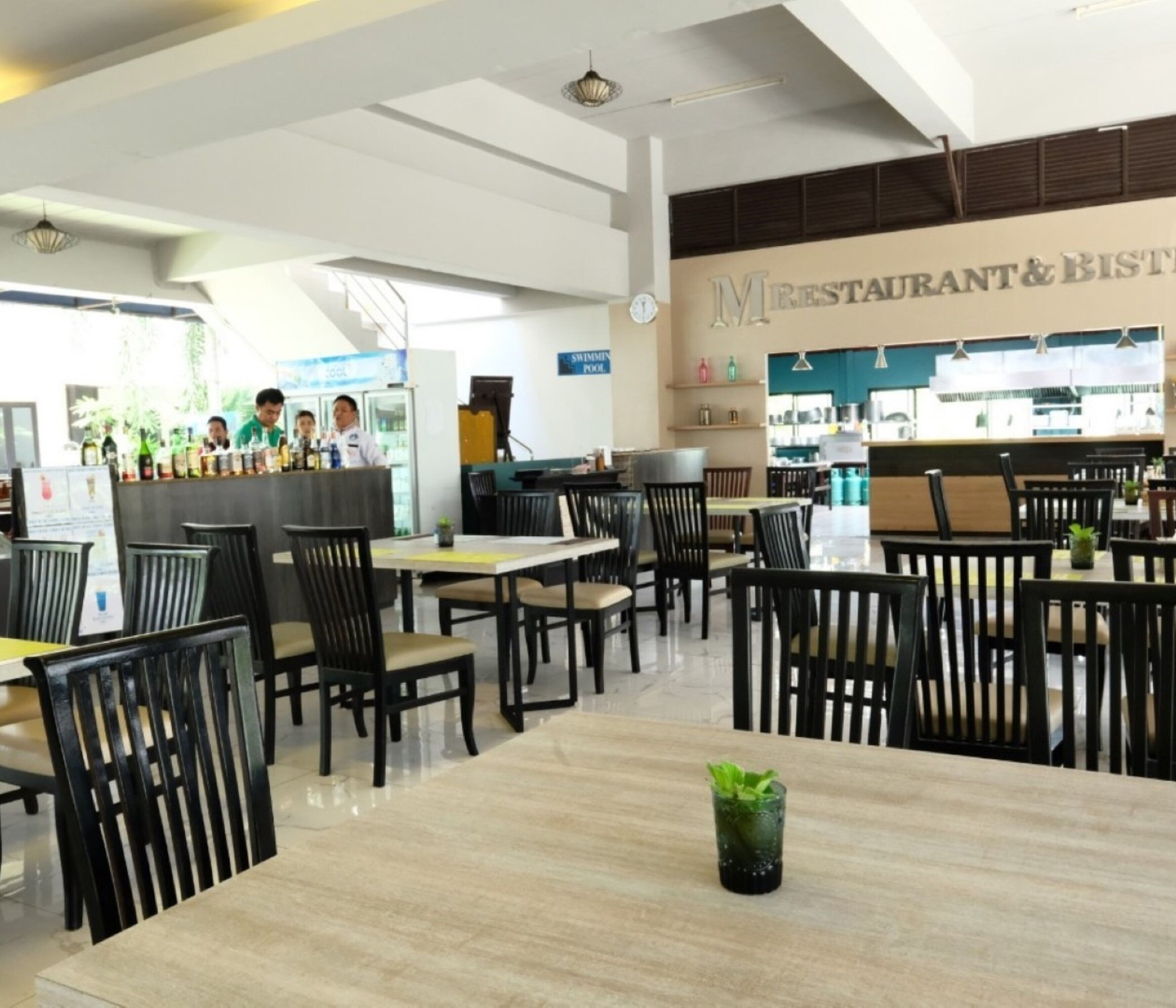 A restaurant with multiple tables and chairs, a bar area, and a sign indicating a swimming pool.