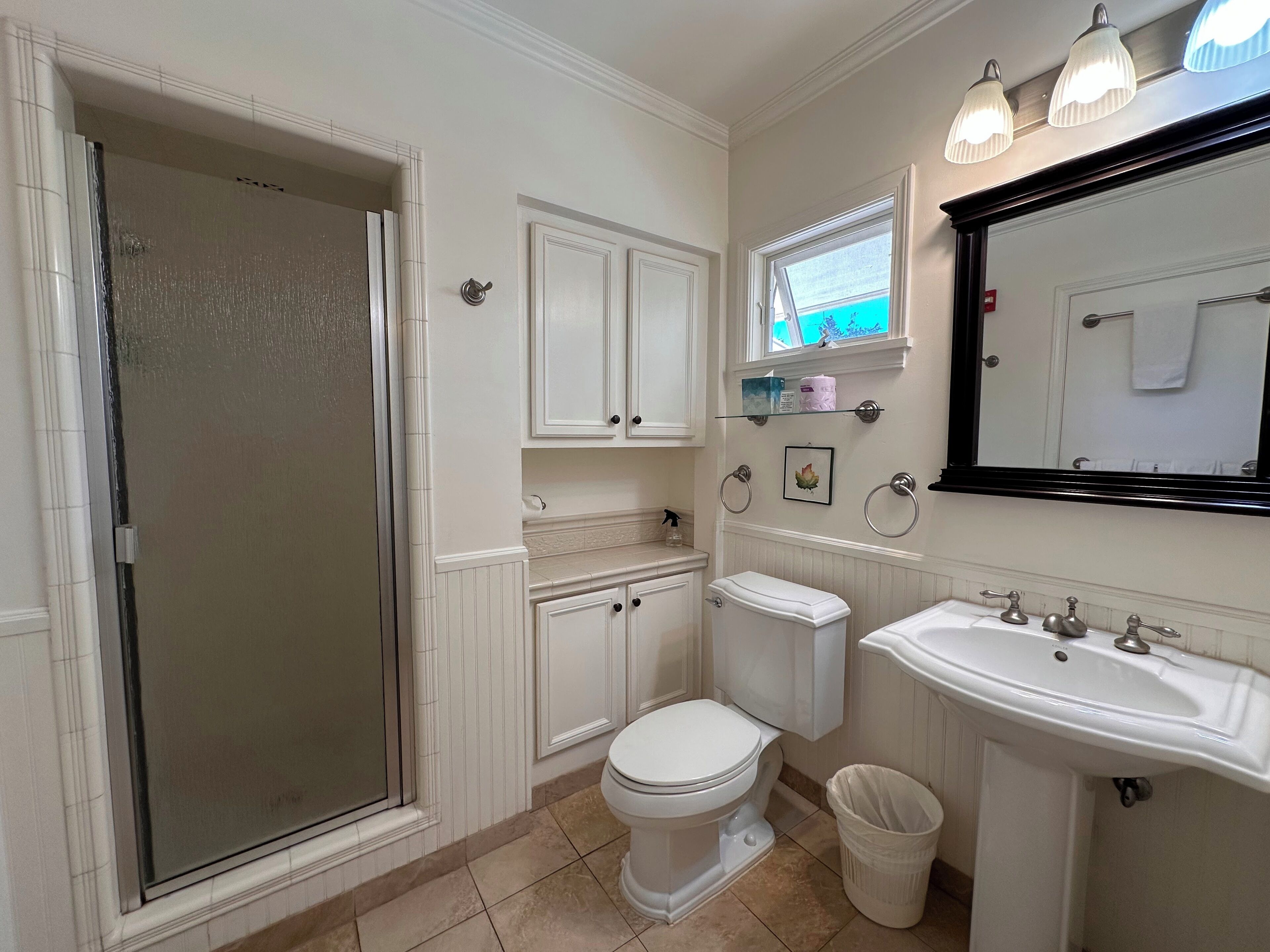 A bathroom with a shower, toilet, sink, and vanity.