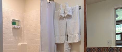 Un baño con ducha, inodoro y un mueble de madera.