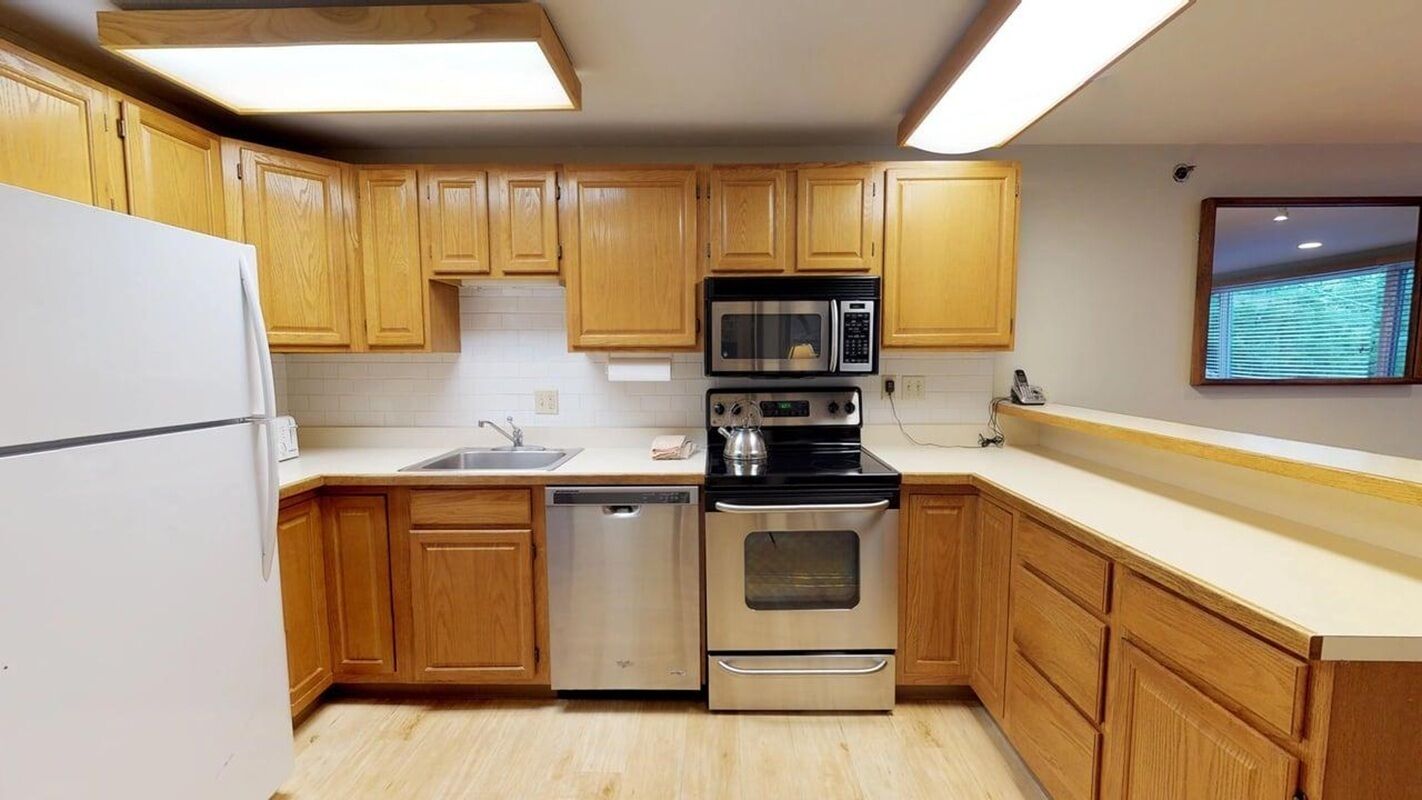 A kitchen with wooden cabinets, a stainless steel refrigerator, a microwave, an oven, and a dishwasher.