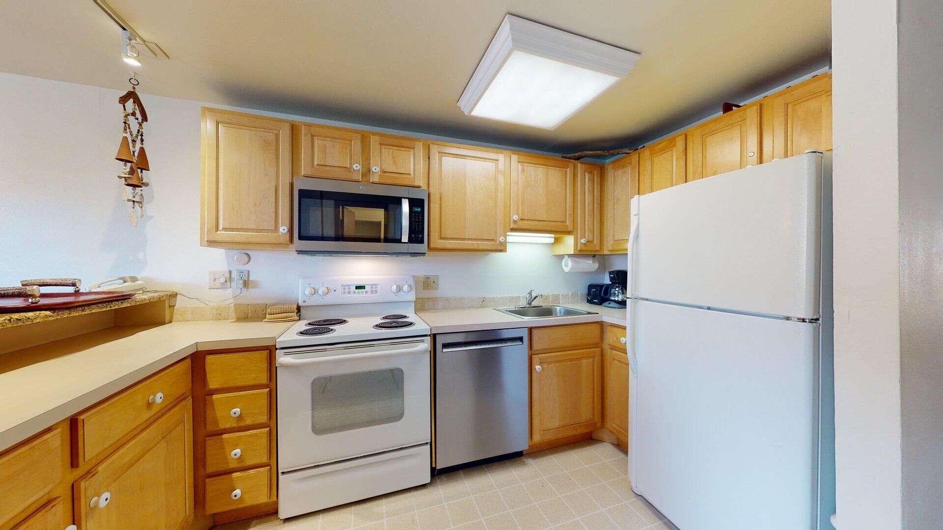 A kitchen with wooden cabinets, a microwave, a stove, a dishwasher, and a refrigerator.