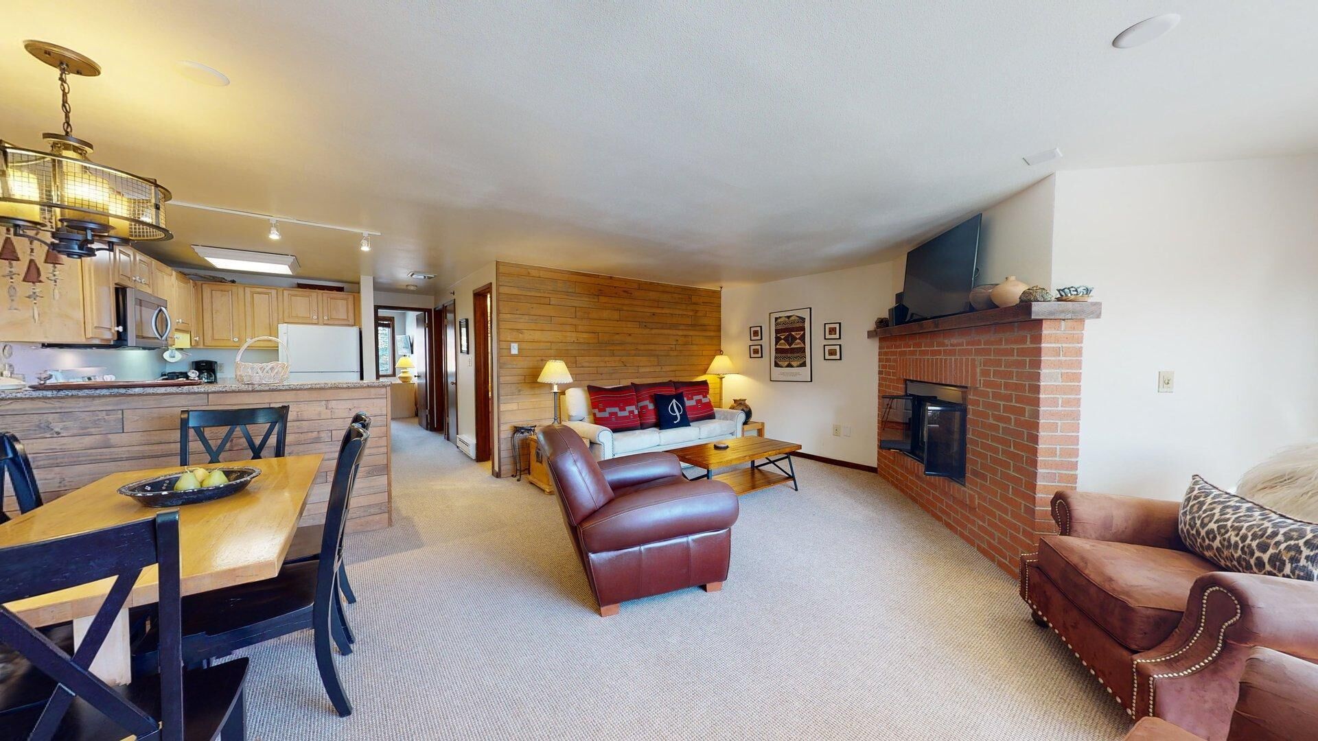 A modern living room with a fireplace, leather sofas, and a dining area with a table and chairs.
