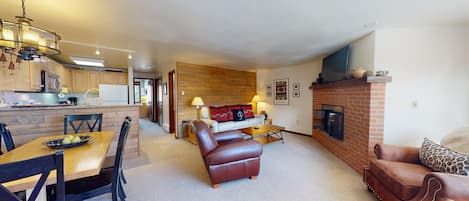 A modern living room with a fireplace, leather sofas, and a dining area with a table and chairs.