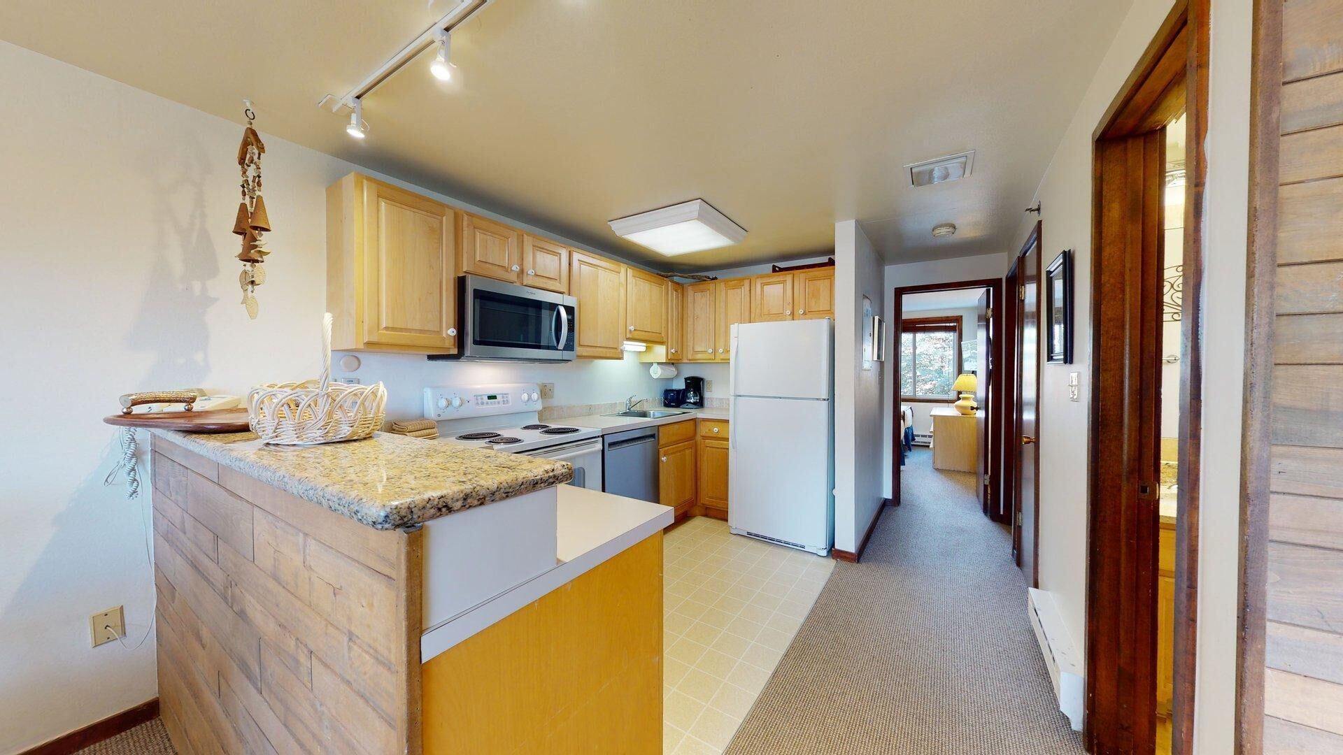 A kitchen with wooden cabinets, a microwave, a stove, and a refrigerator.