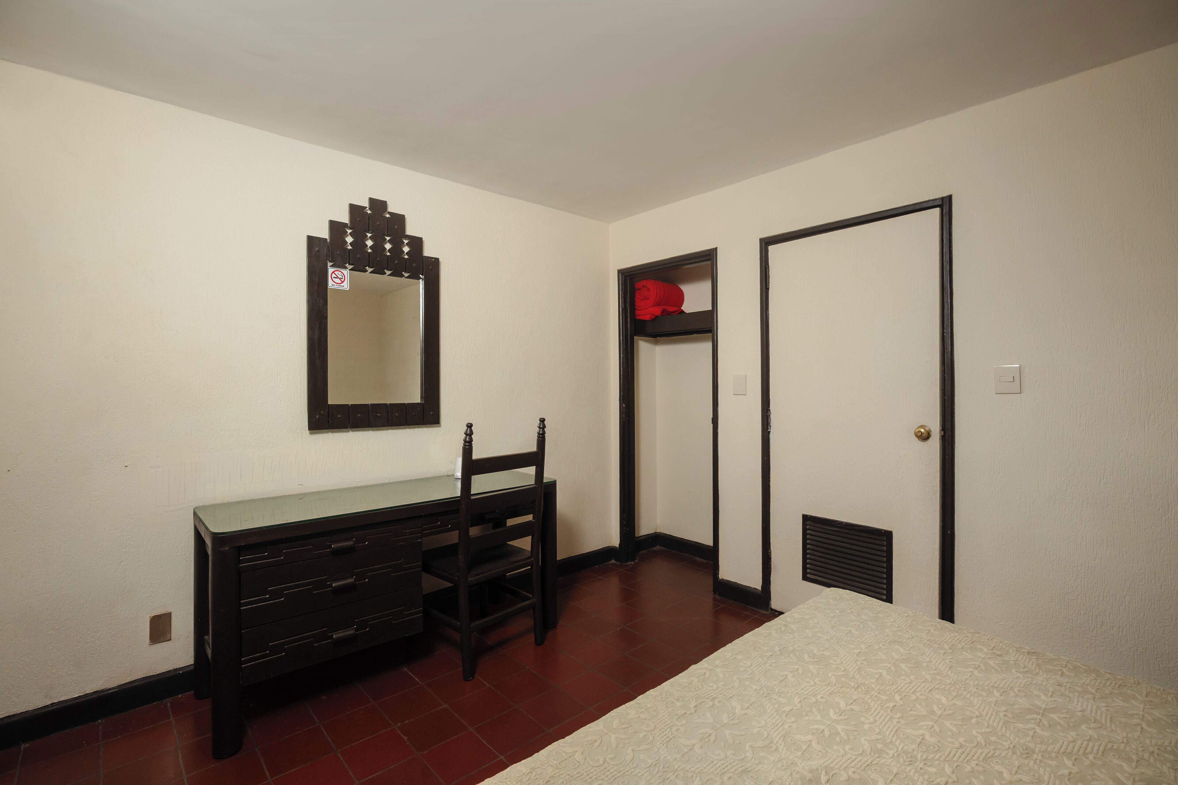 Un dormitorio con cómoda, silla, cama, armario y puerta.