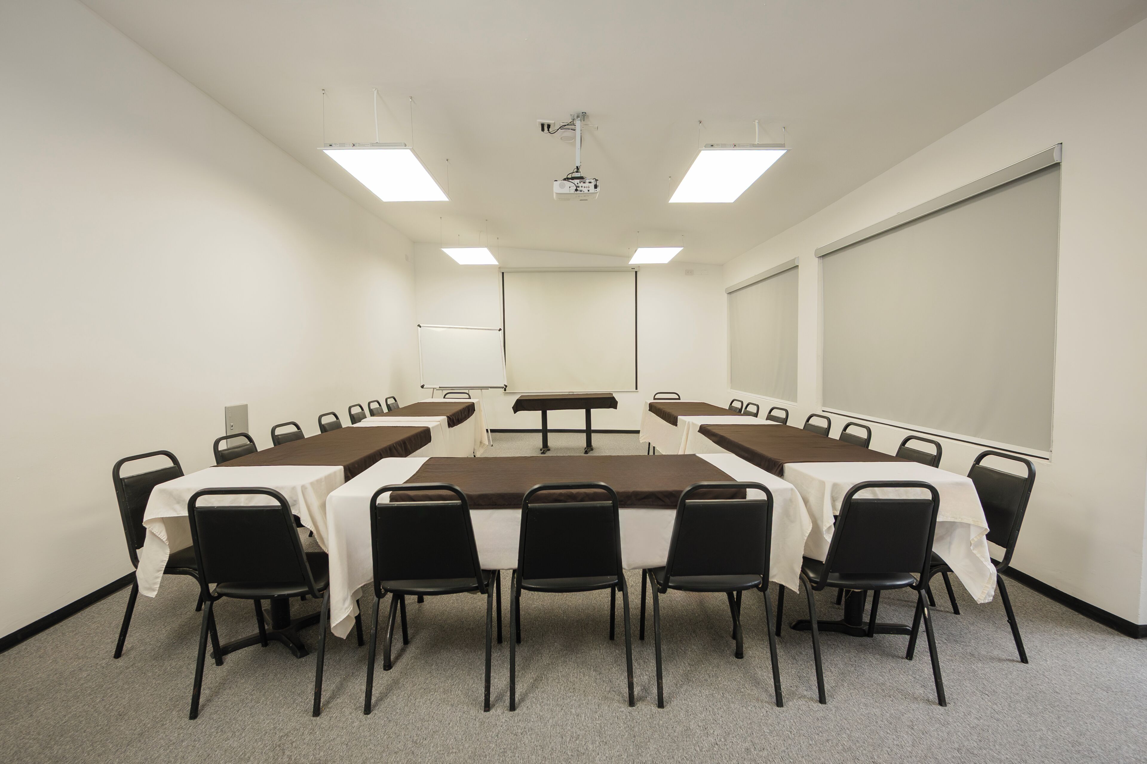 A conference room with a long table, chairs, a projector, and a screen.