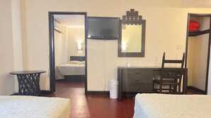 Une chambre d’hôtel avec deux lits, un bureau, une chaise, une télévision et un miroir.