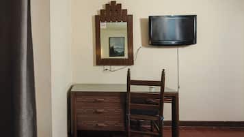 Una habitación con un aparador de madera, una silla, un televisor montado en la pared y un espejo con un marco decorativo.
