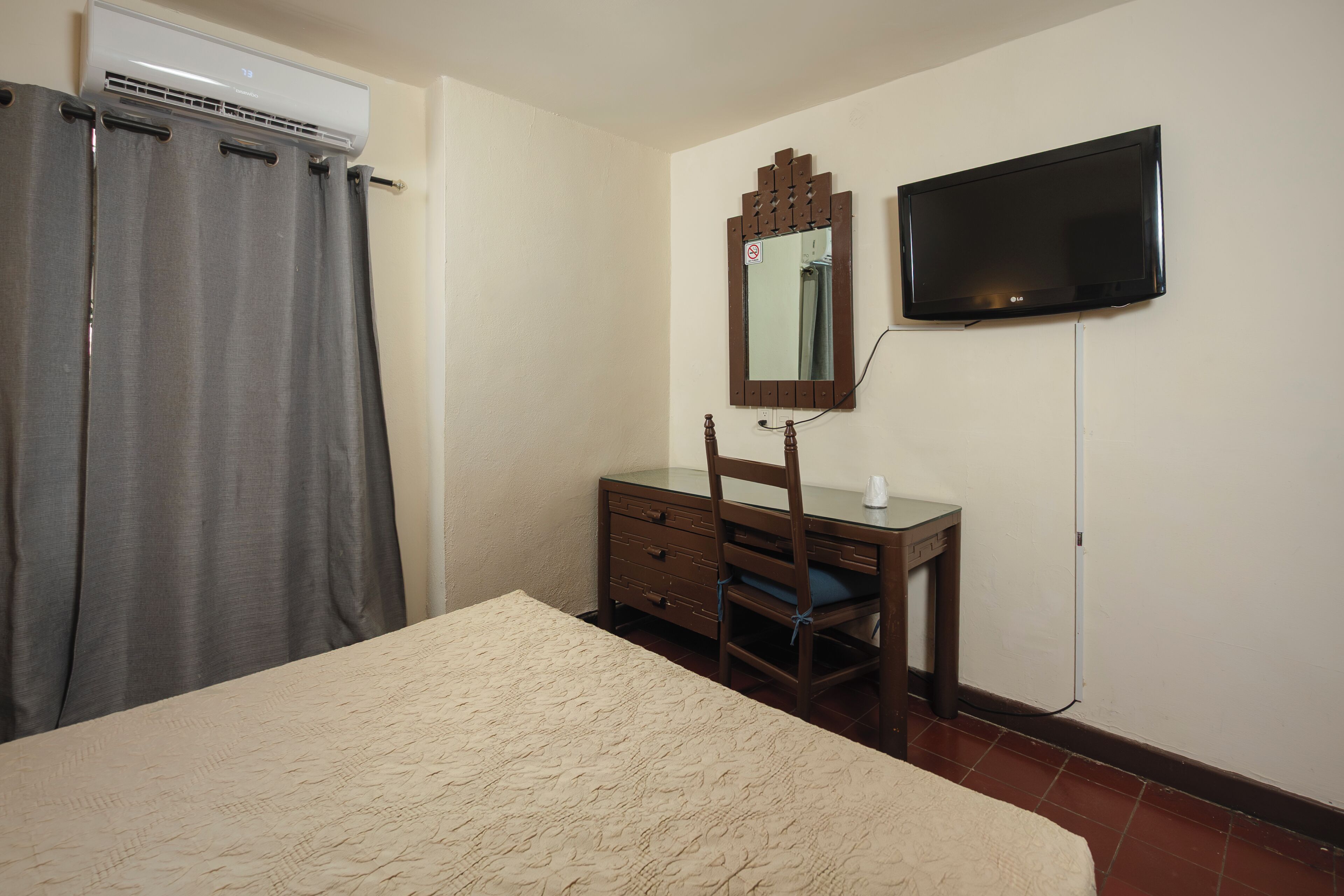 A bedroom with a bed, a dresser, a mirror, and a television.