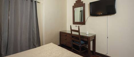 A bedroom with a bed, a dresser, a mirror, and a television.