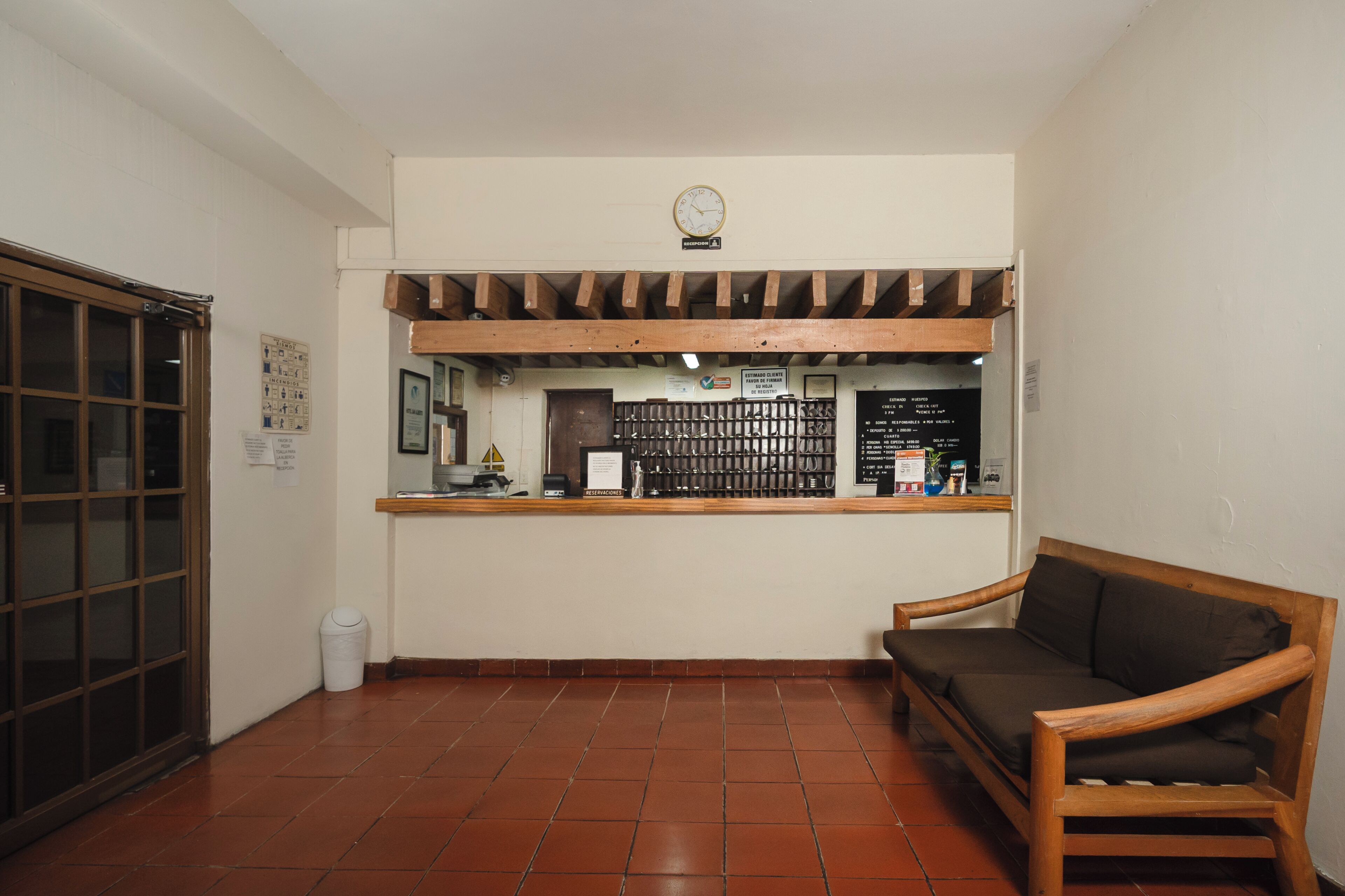 Un área de recepción con un mostrador de madera, un reloj encima y piso de baldosas.