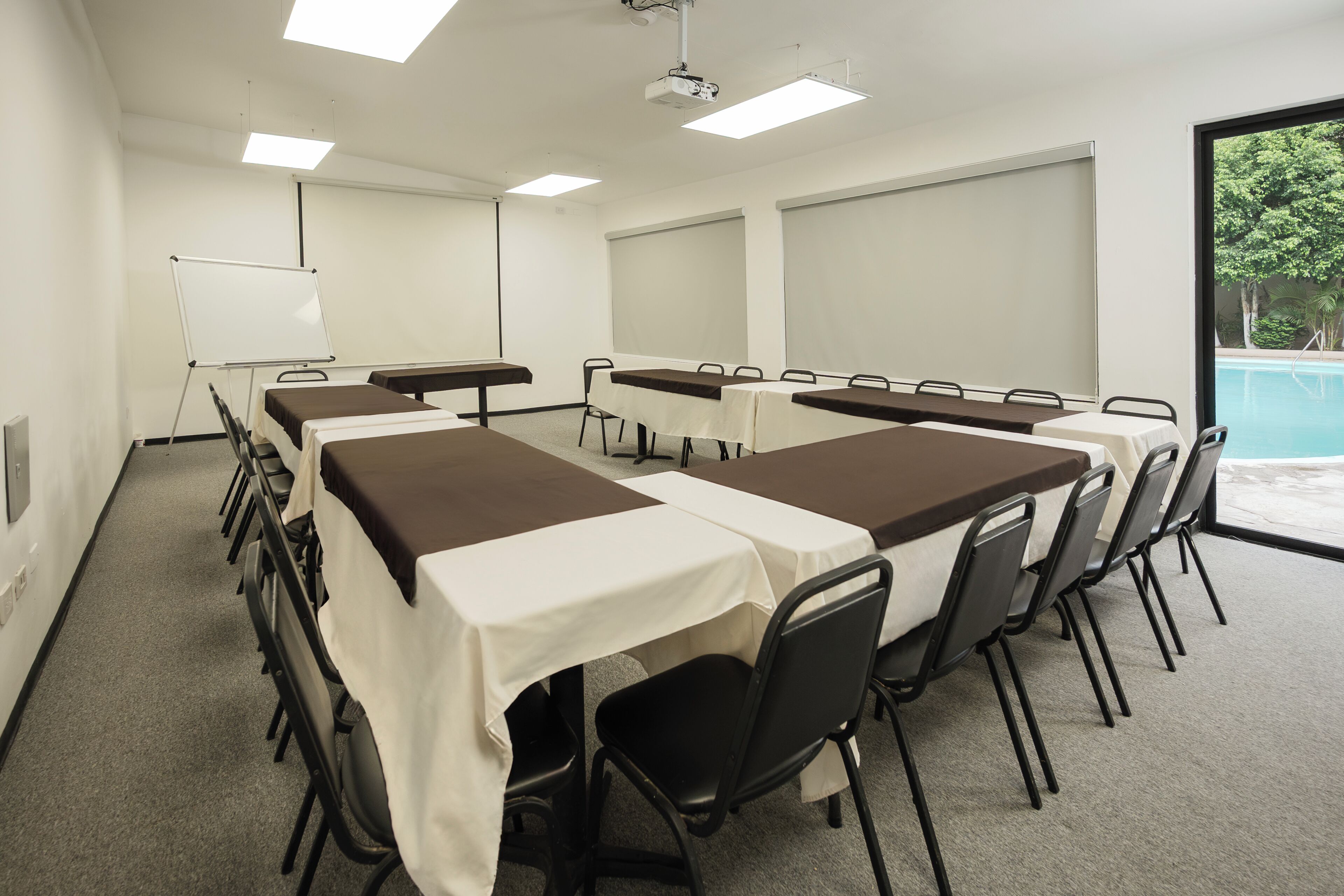 Uma sala de conferência com uma mesa comprida, cadeiras, um quadro branco e um projetor.