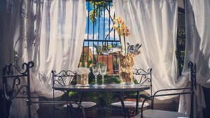 An outdoor patio with a table set for two, surrounded by white curtains, and a decorative vase with flowers. - Antica Locanda (Rome)