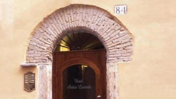 A hotel entrance with a stone archway and a wooden door. - Antica Locanda (Rome)