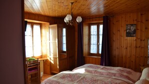 A wooden-paneled room with a bed, a desk, and a chair. - Hotel Les Touristes (Abondance)