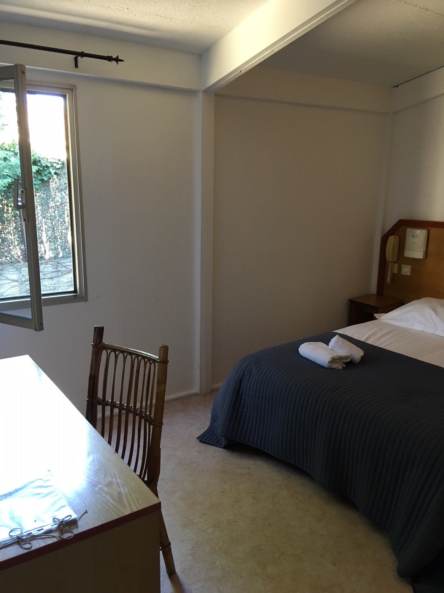 Quarto com cama, cadeira, mesa e janela.