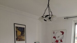 Ett hotellrum med två sängar, vita sängkläder, röda plädar, en vas med blommor, ett inramat konstverk och en väggmonterad lampa.
