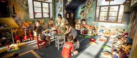 Una habitación con zona de juegos, un ventanal grande y un mural en la pared.