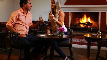 A couple seated at a round table with a fireplace in the background.