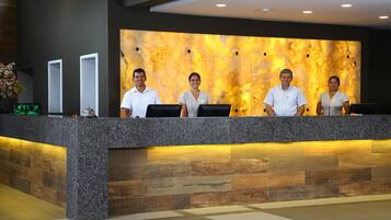 A reception desk with four staff members, a marble wall, and a wooden panel design.