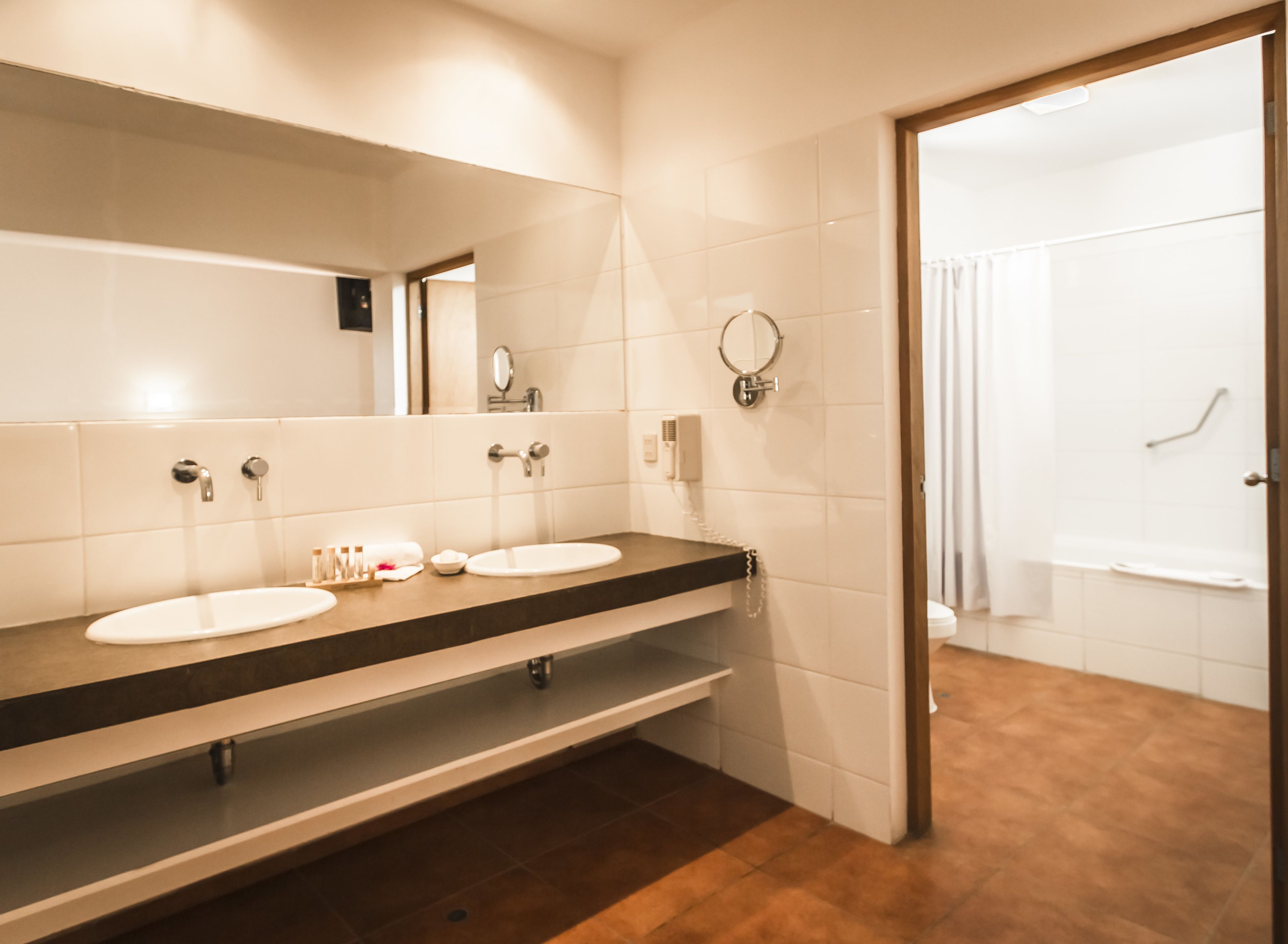 A modern bathroom with two sinks, a mirror, a towel rack, and a shower area.