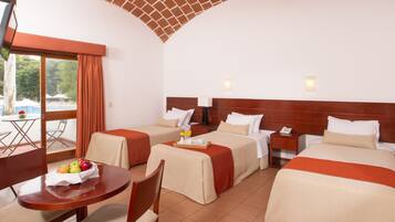 Habitación de hotel con dos camas individuales, una mesa de comedor con desayuno y vistas al exterior.