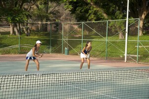 Una cancha de tenis al aire libre con una red en primer plano.