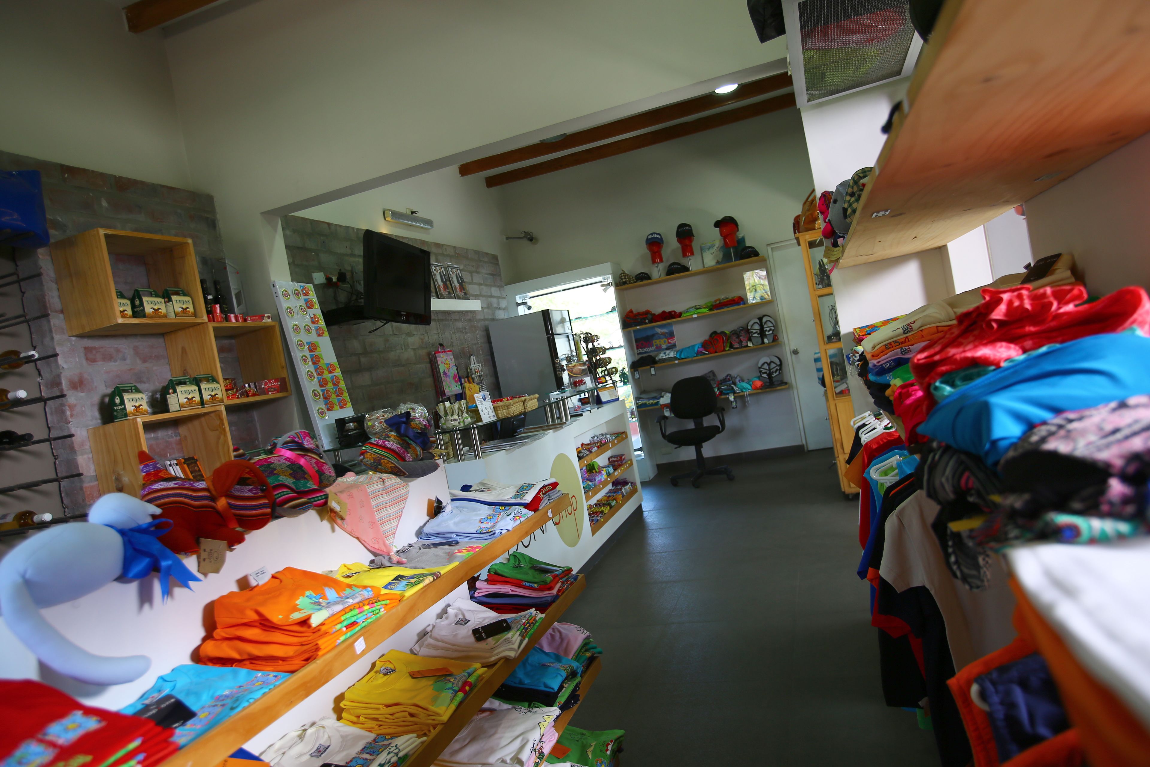 A clothing store with shelves of folded clothes and a variety of items on display.
