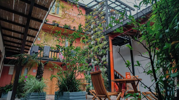 A rooftop garden with potted plants, wooden furniture, and a metal staircase. - Masaya Bogotá (Bogotá)