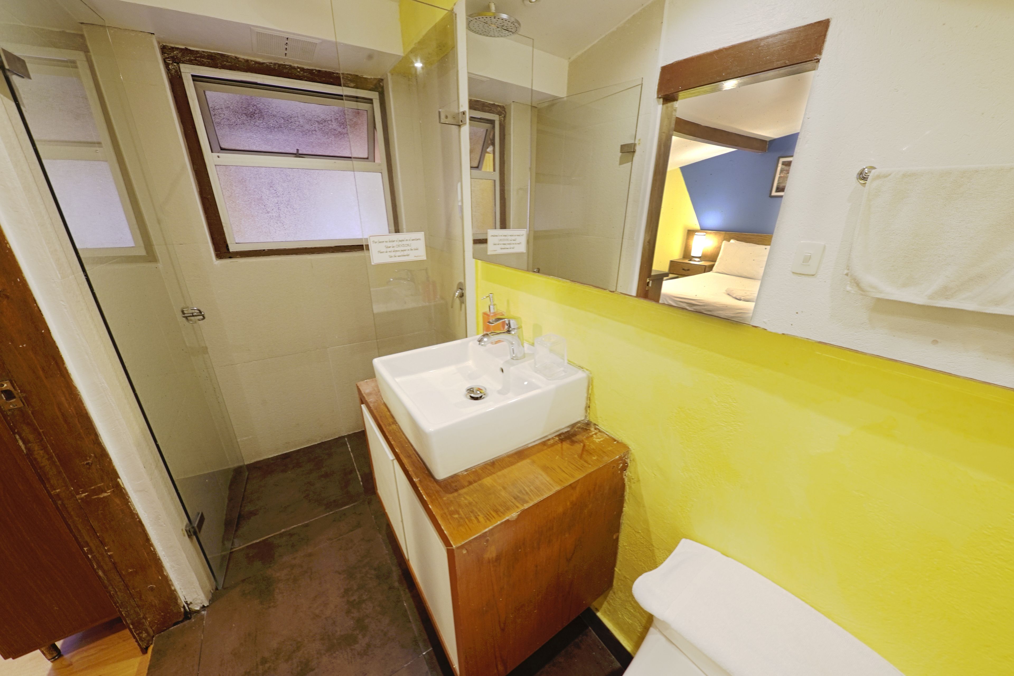 A bathroom with a wooden vanity, a white sink, a mirror, and a towel rack.
