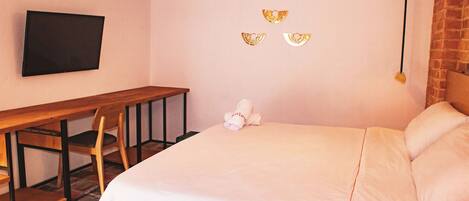 Ein Schlafzimmer mit einem Bett, einem Schreibtisch, einem Stuhl und einem an der Wand befestigten Fernseher.