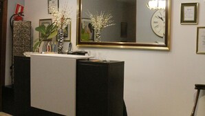 Una recepción con un espejo, cuadros enmarcados y un reloj en la pared.