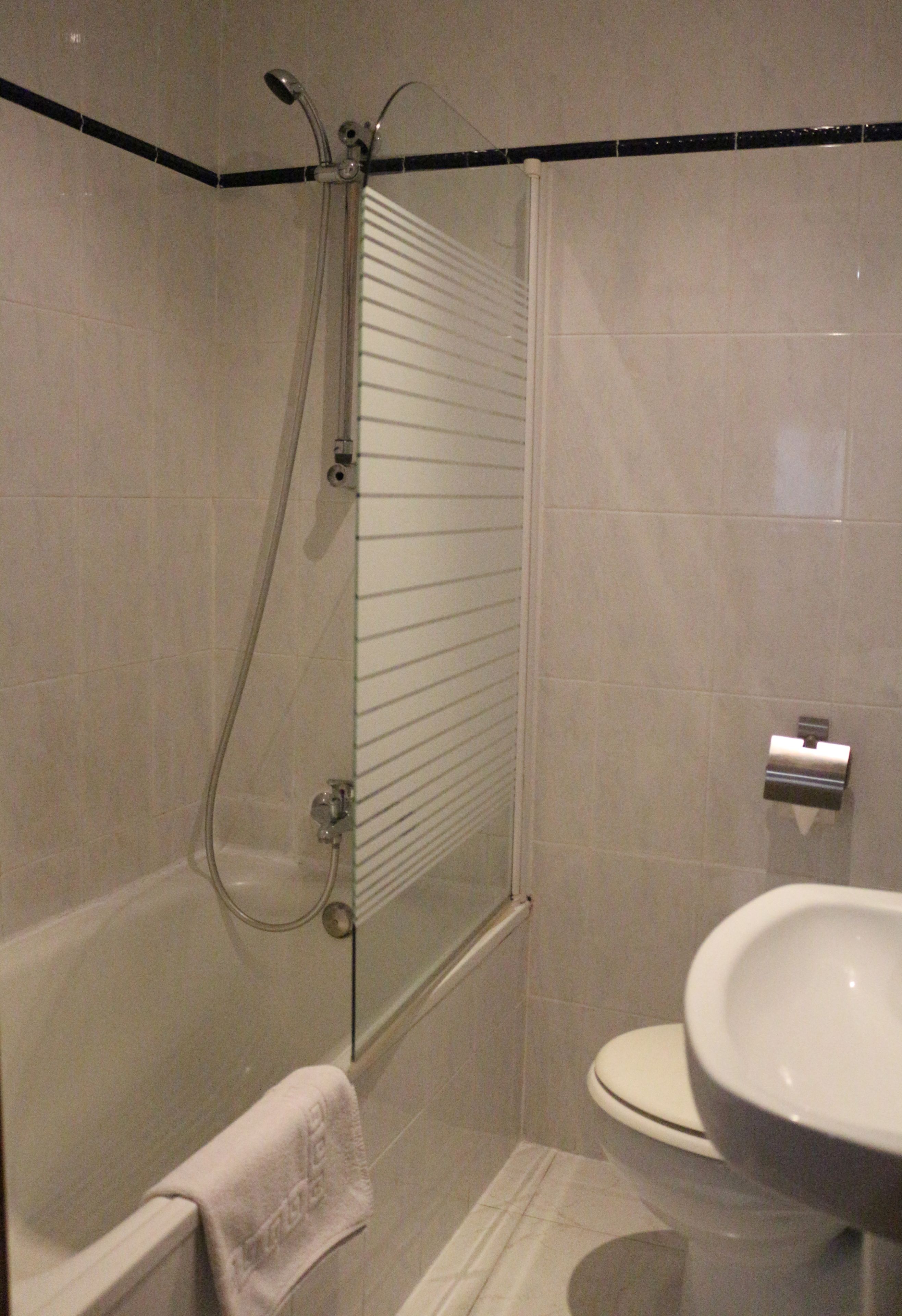 A bathroom with a shower, toilet, and sink.