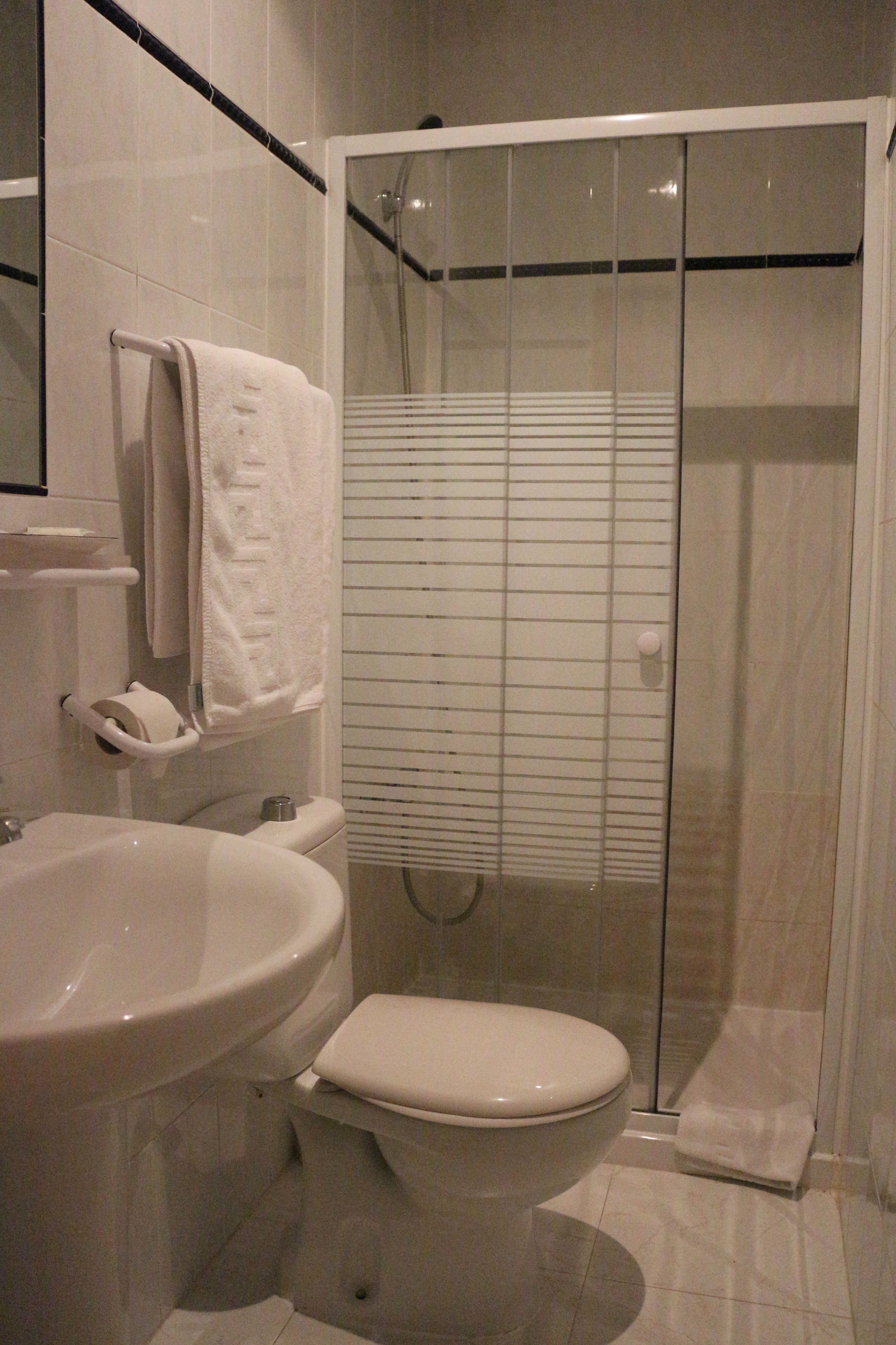 A bathroom with a toilet, sink, and glass-enclosed shower.