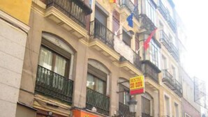 Un edificio con escaparate cerrado, un letrero que dice "YIMBATAN" y balcones adornados con banderas.
